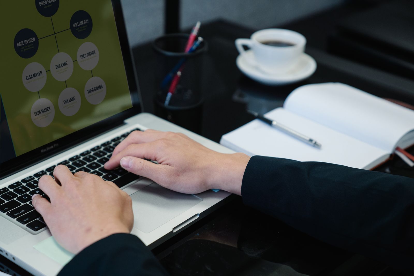 Person typing a cover letter draft on a laptop at a desk with notebook and coffee nearby