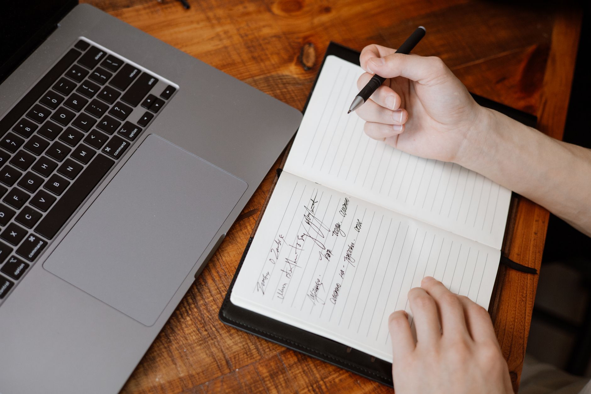 A job seeker at a laptop reviewing a job search dashboard with multiple open browser tabs and a notebook of notes beside them