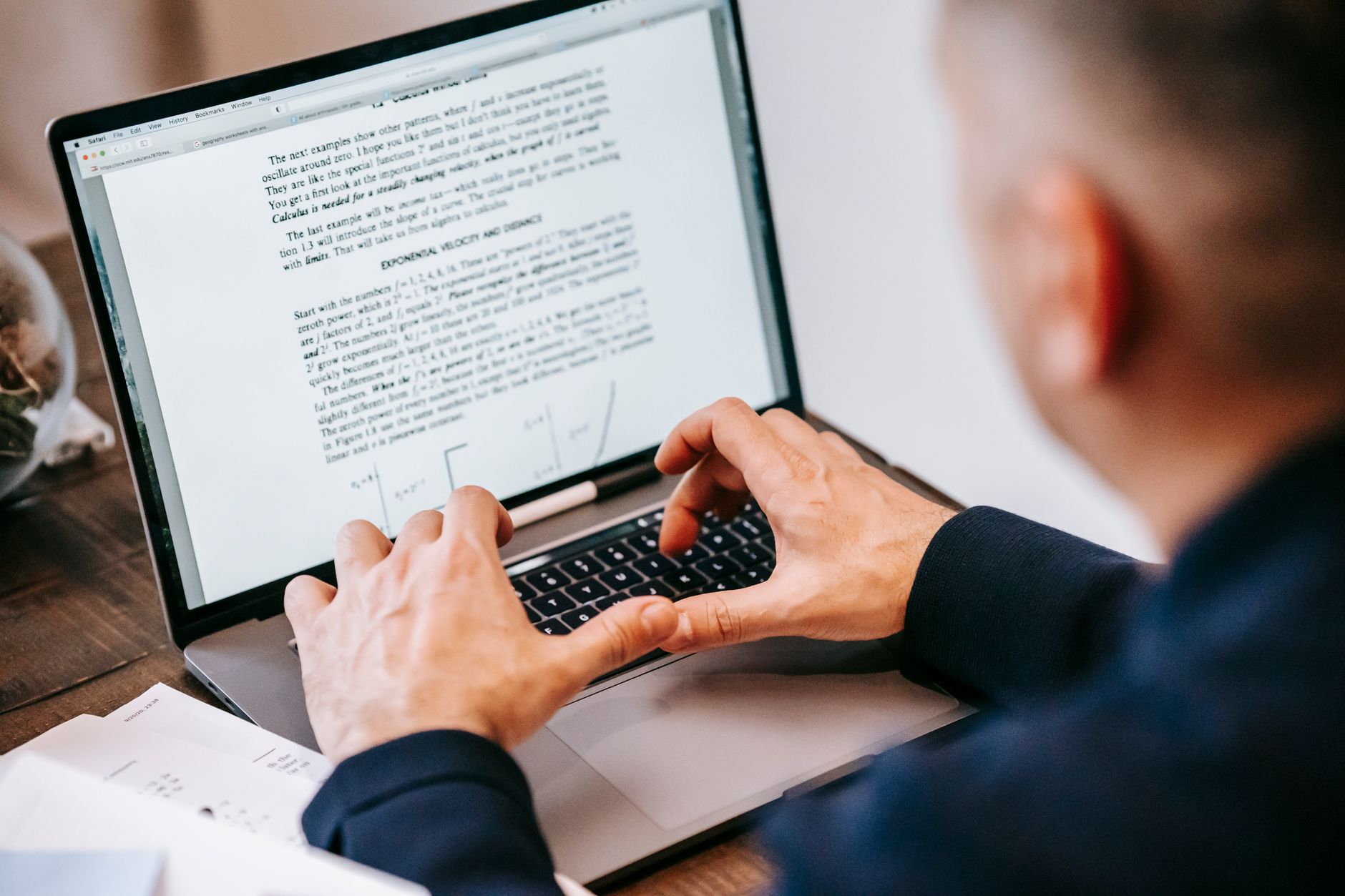 A person sitting at a laptop reviewing a resume draft on screen, coffee cup beside the keyboard, soft natural light from a window