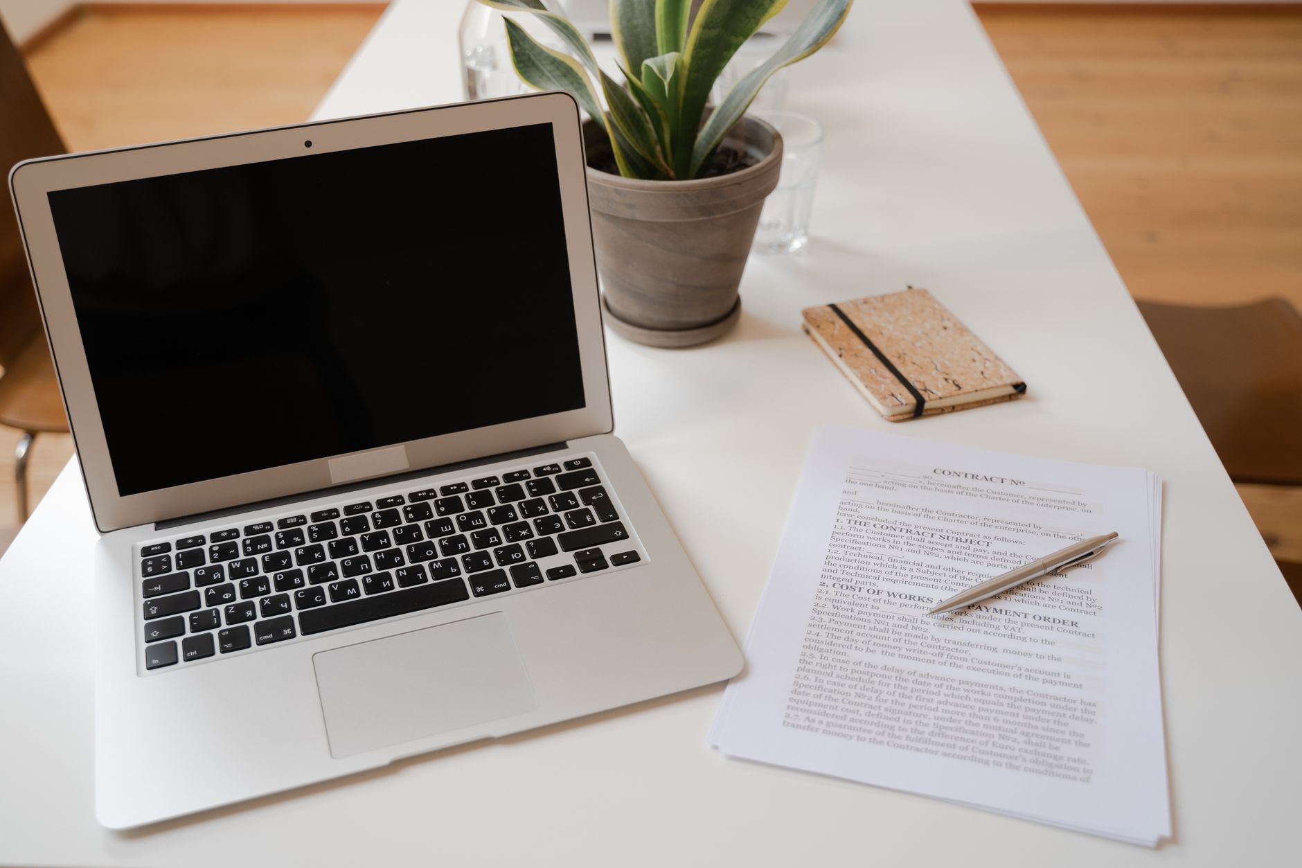 Close-up of a printed CV document on a desk next to a laptop showing a CV template, with a pen resting on top