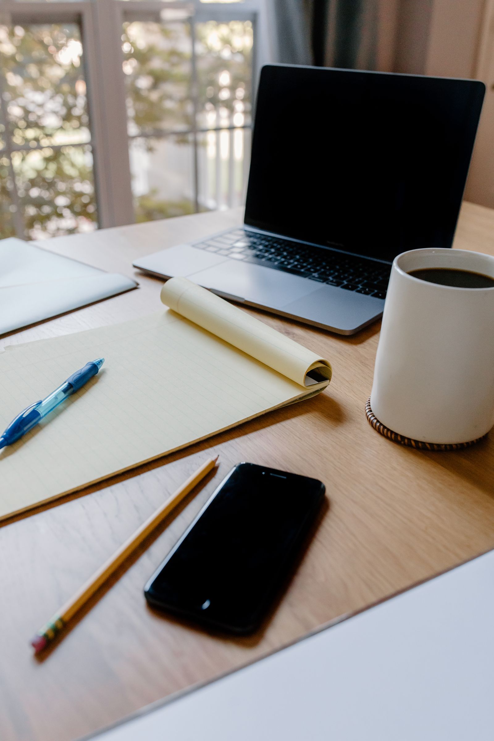 A person reviewing a resume draft on a laptop at a home desk, coffee cup nearby