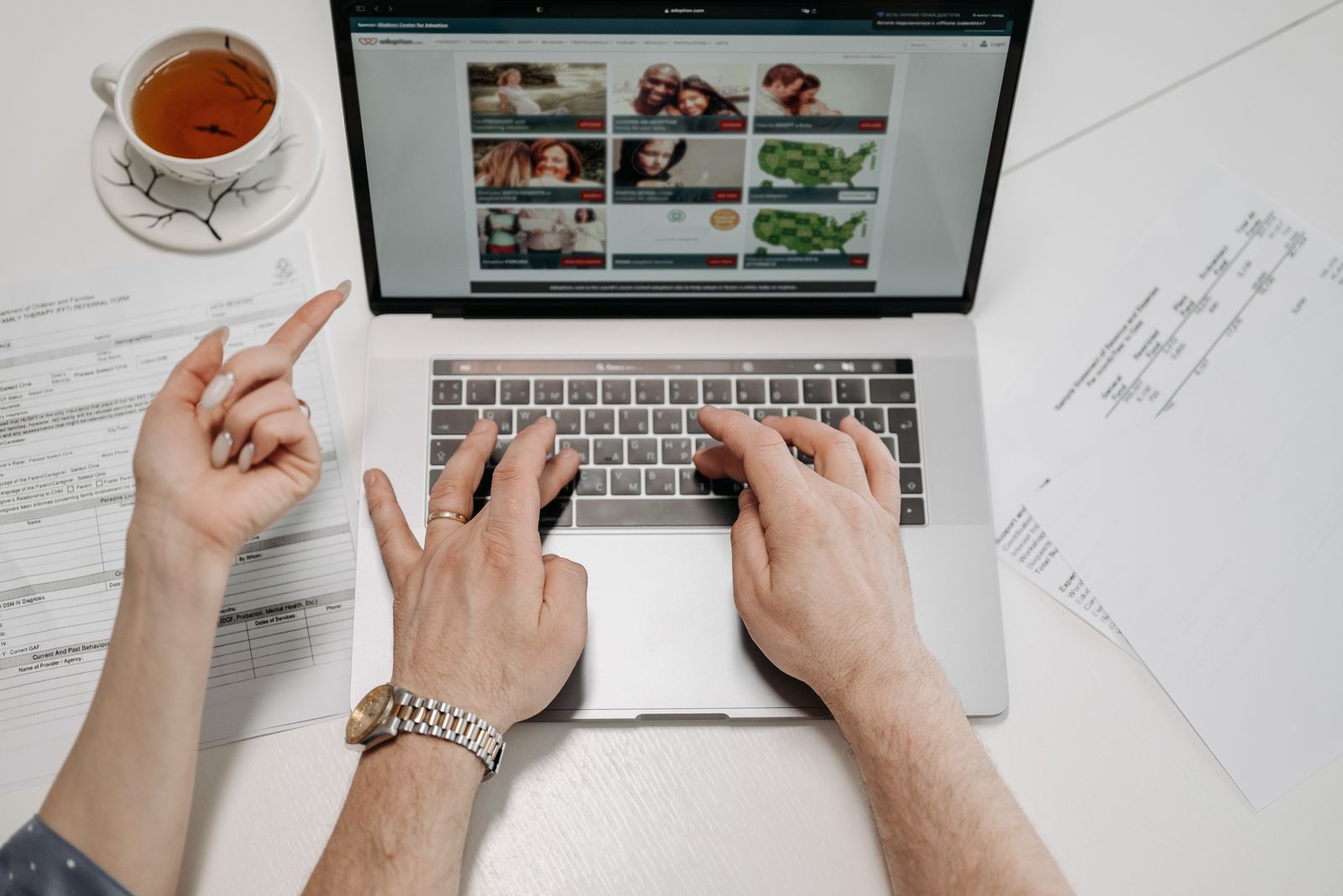 A person typing an email on a laptop at a wooden desk, with a printed resume and coffee cup nearby