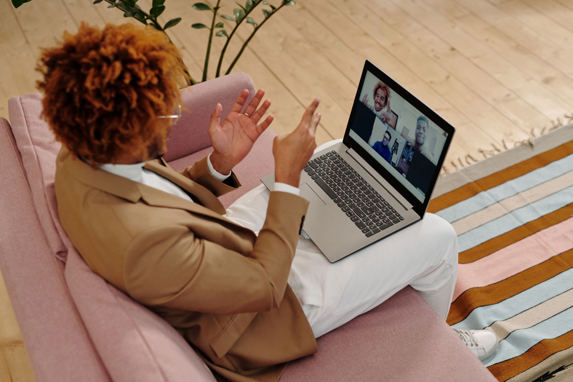 A person sitting on a sofa taking a video call on a laptop