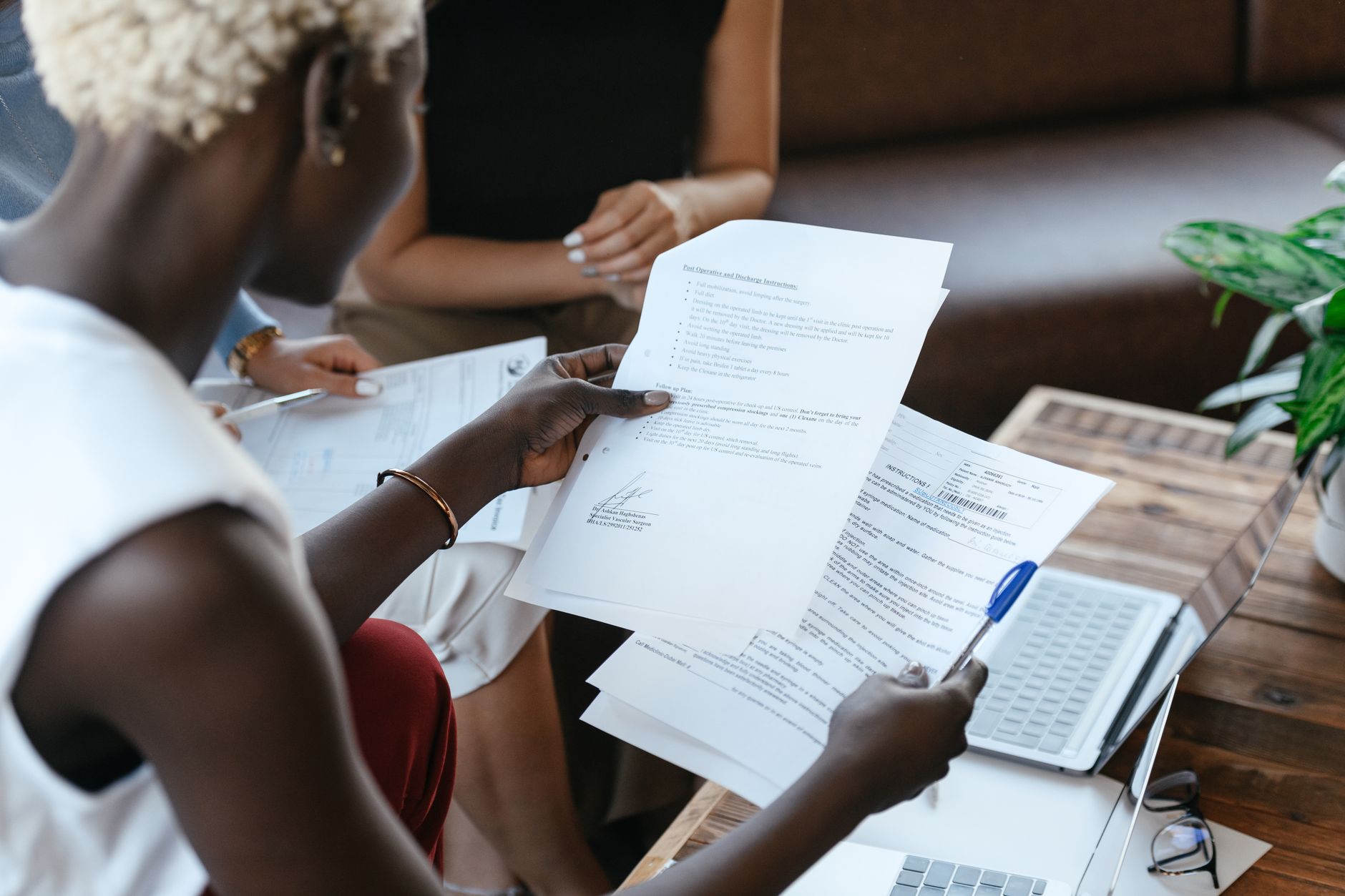 A person sitting at a laptop comparing two printed resume drafts side by side on a desk