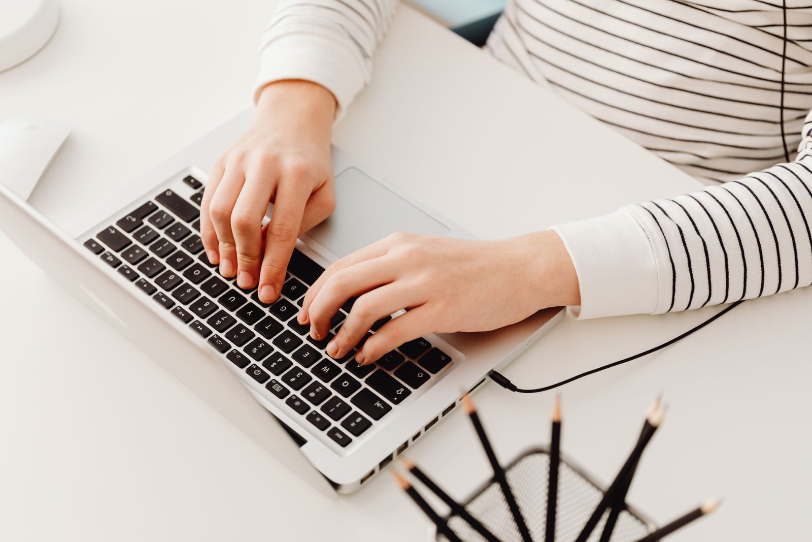 Person typing on a laptop with a resume draft and a job posting open side by side